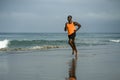 Athletic full body portrait of young attractive and fit black afro American man running on the beach doing Summer fitness jogging Royalty Free Stock Photo