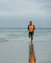 Athletic full body portrait of young attractive and fit black afro American man running on the beach doing Summer fitness jogging Royalty Free Stock Photo