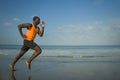 Athletic full body portrait of young attractive and fit black afro American man running on the beach doing Summer fitness jogging Royalty Free Stock Photo