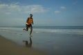 Athletic full body portrait of young attractive and fit black afro American man running on the beach doing Summer fitness jogging Royalty Free Stock Photo