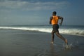 Athletic full body portrait of young attractive and fit black afro American man running on the beach doing Summer fitness jogging Royalty Free Stock Photo