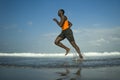 Athletic full body portrait of young attractive and fit black afro American man running on the beach doing Summer fitness jogging Royalty Free Stock Photo