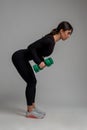 Athletic girl doing dumbbell triceps kickback on grey background Royalty Free Stock Photo