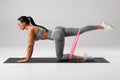 Athletic girl doing kickback exercise for glutes with resistance band. Fitness woman working out donkey kicks Royalty Free Stock Photo