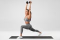 Athletic girl doing lunges exercises with dumbbell, leg muscle training. Fitness woman doing front forward one leg step lunge Royalty Free Stock Photo