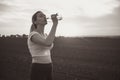 athletic girl drinking water after running distance in a field at sunset, young woman quenches thirst after training from bottle Royalty Free Stock Photo