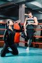 Athletic girl drinks clean water from a bottle in a boxing ring. an athletic muscular man stands behind. Royalty Free Stock Photo