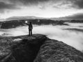 Girl on rocky edge above foggy cloud  illuminated misty world Royalty Free Stock Photo