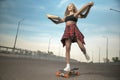 Girl jumping off a skateboard with headphonesGirl neither skateboard or longboard delivers pizza in the city Royalty Free Stock Photo