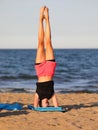 athletic girl performs challenging gymnastic exercises on the beach by the sea with shorts