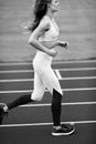 Athletic girl running at the stadium, working out, keep herself in shape, wearing sportswear, white top and pants Royalty Free Stock Photo