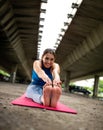 Athletic girl stretching sitting bending forward touching toes outdoors Royalty Free Stock Photo