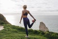 athletic girl in stylish sportswear stretching leg on cliff near sea Etretat France Royalty Free Stock Photo