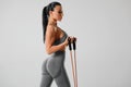 Athletic girl working out with resistance band on gray background. Fitness woman exercises with expander