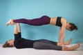 Two athletic girls working out, doing yoga on blue background. Strength and motivation, sport and healthy lifestyle