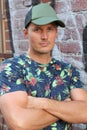 Athletic guy in a floral tee shirt and a baseball cap on urban background Royalty Free Stock Photo