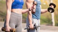 Athletic guy and girl doing exercises with dumbbells at the sports field Royalty Free Stock Photo