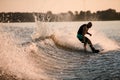 Athletic guy holds rope and riding wakeboard on splashing river wave. Royalty Free Stock Photo