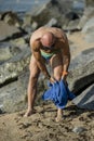 Athletic guy toweling off his legs with swim glasses in a beach with rocks. Fit handsome man with a blue towel after Royalty Free Stock Photo