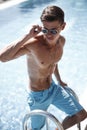 Athletic guy in trendy sunglasses is posing near the swimming pool Royalty Free Stock Photo