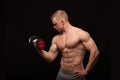 Athletic handsome man fitness-model is working out with dumbbell and showing his perfect body. isolated on black Royalty Free Stock Photo