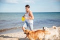 Athletic handsome man playing with his dog on the beach Royalty Free Stock Photo