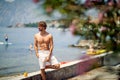 Athletic handsome man posing on deck by water. Background of sea and European city. Lifestyle, sport, fashion, holiday concept Royalty Free Stock Photo