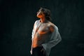 Athletic, handsome young man with muscular body against dark textured studio background. Young man in white shirt and Royalty Free Stock Photo