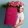 Smiling man delivery guy with rose at ear and lipstick kiss on his cheek is holding huge valentines day box with flowers Royalty Free Stock Photo