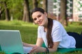 Athletic healthy girl in a white t shirt working on a computer in nature and looking into the frame