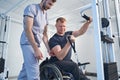 Athletic injured young man does weight exercise on cable simulator