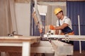 Handsome man carpenter using woodworking machine in workshop Royalty Free Stock Photo