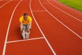 Athletic male in yellow sportswear sitting at the stadium track, doing a warm up before running, stretching legs Royalty Free Stock Photo