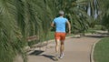 Athletic man in blue tshirt runnings along the tropical park pathway Royalty Free Stock Photo