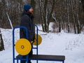 Athletic man bodybuilder training lifting barbell outdoors on winter day. Bearded guy doing strength exercises Royalty Free Stock Photo