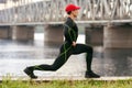 Athletic man doing stretching exercises, outdoor. Active male working out outside on the background of the bridge Royalty Free Stock Photo