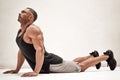 Strong and muscular athlete posing in a bright studio while doing a lion yoga pose