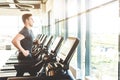 The athletic man dressed in a black sportswear running on the treadmill in the modern gym