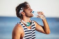 Man with fit body holding bottle of refreshing water, resting after workout or running at beach Royalty Free Stock Photo