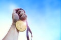 Athletic man hand holding golden coin medal. Royalty Free Stock Photo