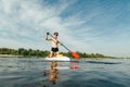 Athletic man paddles while sitting on a sup board floats on a pond. Surfing on the river on a sup board Royalty Free Stock Photo