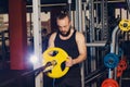 Athletic man puts on plate for barbell in the gym Royalty Free Stock Photo