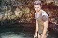 Athletic man in the sea or ocean by rocks, wet t-shirt Royalty Free Stock Photo