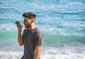 Young man by the sea sending voice message on phone Royalty Free Stock Photo