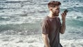 Young man by the sea sending voice message on phone Royalty Free Stock Photo