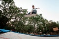 Athletic man with skateboard simulator jumps on trampoline against the backdrop of green trees Royalty Free Stock Photo