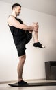 Athletic man standing on one leg and stretching another. Workout on black yoga mat. Muscular young man practicing yoga