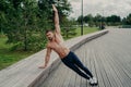 Athletic man stands in side plank pose, raises one arm, poses with shirtless torso, wears trousers and sneaks. Sportsman exercises Royalty Free Stock Photo