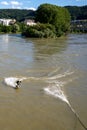 Athletic man surfing on the Rhine River with a bungee cord attached to a bridge