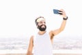 Athletic man taking selfie photo on the hill over the city with phone